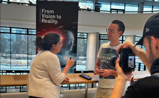 Daniel Chrobot bei einem Interview vor einem From-Vision-to-Reality-Banner